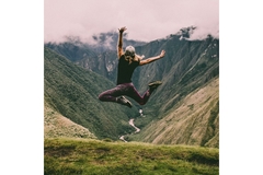 Person jumping outside between mountains.